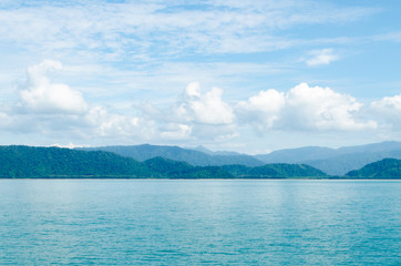 Horizontal of Seascape including Forest Mountain, Blue Sky and Wave of Water Foam in Ocean.