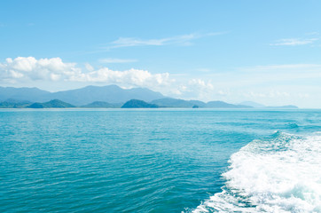 Horizontal of Seascape including Forest Mountain, Blue Sky and Wave of Water Foam in Ocean.