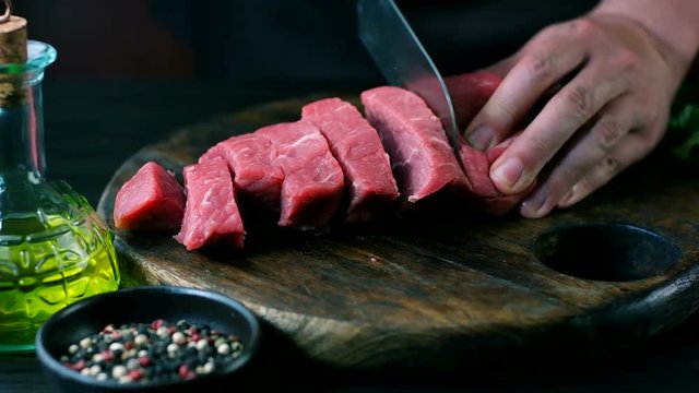 Man cut raw beef on steak pieces