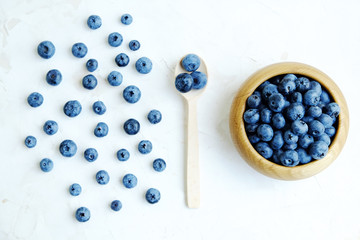 Freshly picked blueberries on white, spoon with blueberry and bowl with blueberry. Flat lay.