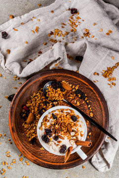 Ideas for an autumn winter breakfast. Spicy yoghurt with granola, dried berries, nuts, almonds, spices (cinnamon, anise), in cup, on plate. Gray background, copy space top view