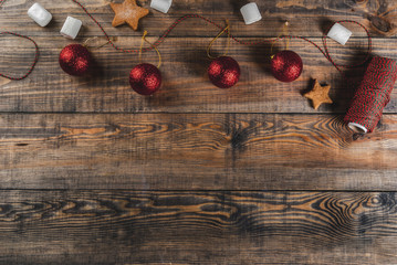 Celebrations of Christmas, New Year's background. Wooden table with decorations, festive rope, Christmas balls, marshmallow, top view copy space