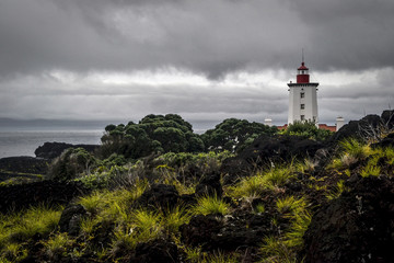 Fototapeta na wymiar white-red beacon at the end of the lagoon coast of Pico Island in the Azores