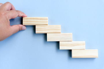 Business Concept - Hand arranging wood block stacking as step stair.