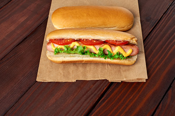 Two tasty Hot Dog laying on craft paper with sausage on wooden background. Above view.