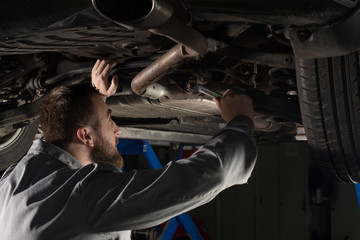 Obraz na płótnie Canvas mechanic under the car using wrench 