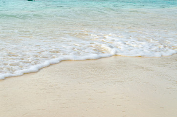 Close up Wave of The Ocean, White Sand on Summer Beach and Surface Water Foam.