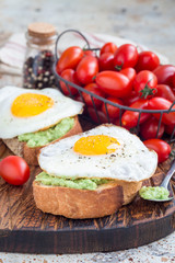 Open sandwich with mashed avocado and fried egg on toasted bread, sprinkled with black pepper, vertical