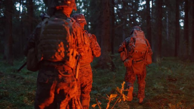 Squad of Five Fully Equipped Soldiers in Camouflage on a Reconnaissance Military Night Mission. They're Lit by Red Flare and Move Through Dense Forest.  Shot on RED EPIC-W 8K Helium Cinema Camera.