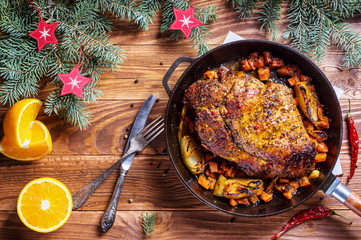 Roasted meat with spices and oranges in pan for Christmas dinner served with fork, knife and...