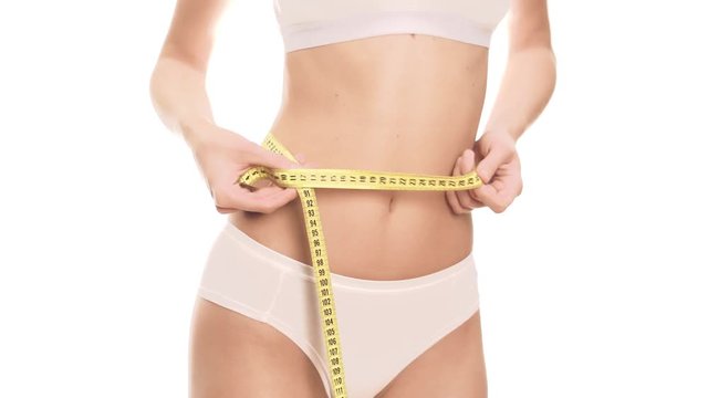 Woman measures her waist with a centimeter. White background.
