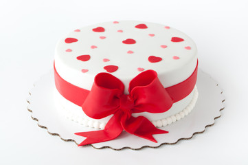 Art cake decorated with red ribbon, bow, hearts. Picture for a menu or a confectionery catalog.