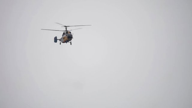 Helicopter From Below Flying Through Cloudy Sky. Helicopter hovering against bright sunny and cloudy sky