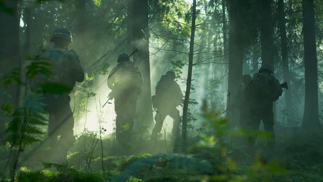 Squad of Five Fully Equipped Soldiers in Camouflage on a Reconnaissance Military Mission, Rifles in Firing Position. They're Running in Formation Through Dense Dark Forest. Side View Long Shot. 