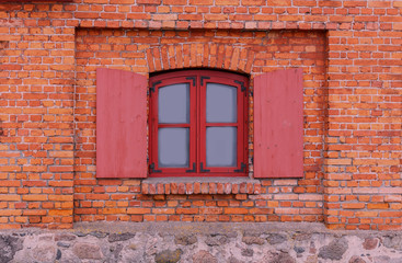 Red window on the facade of the old brick house.