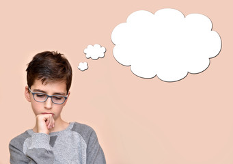 Thoughtful young boy wearing glasses with an empty thought bubble