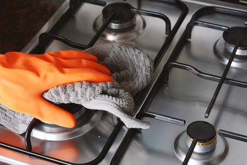 Close up view of hands in rubber gloves cleaning hob