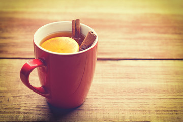 Red cup of hot tea with lemon and cinnamon.