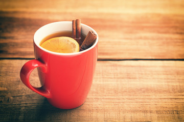 Red cup of hot tea with lemon and cinnamon.