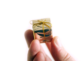 Hand holding a miniature golden christmas parcel. White background.