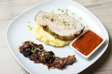 Baked pork with mashed potatoes, fried mushrooms and tomato sauce. Close-up, selective focus.