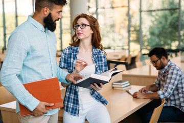 Young attractive students spending time in library