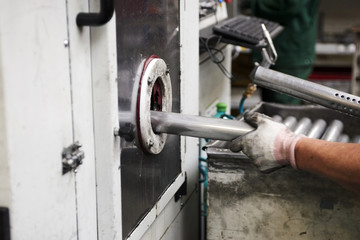 Inside a factory, industrial worker in action on metal machine 