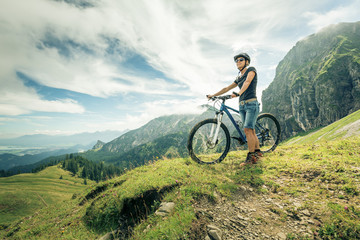 Germany, Bavaria, Pfronten, woman with mountain bike on alpine meadow near Aggenstein