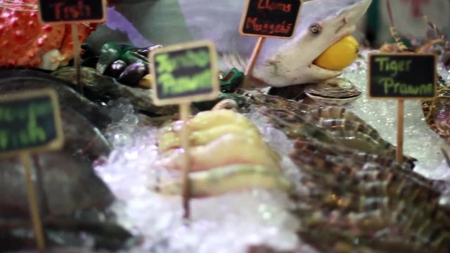 Fresh seafood on ice at the fish market with beautiful blurred bokeh lights. 1920x1080