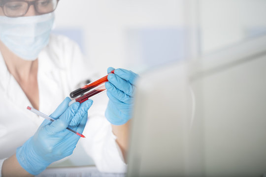 Close-up of lab technician examining test tubes with liquid in laboratory