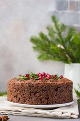 Traditional Christmas English pudding (fruit cake) with rosemary and cranberries on white plate on...