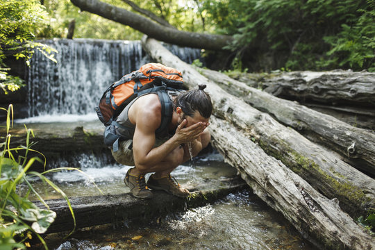 Young man on a hiking trip refreshing at a waterfall
