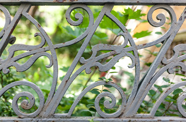 Close up of a grey railing with green leafs in background