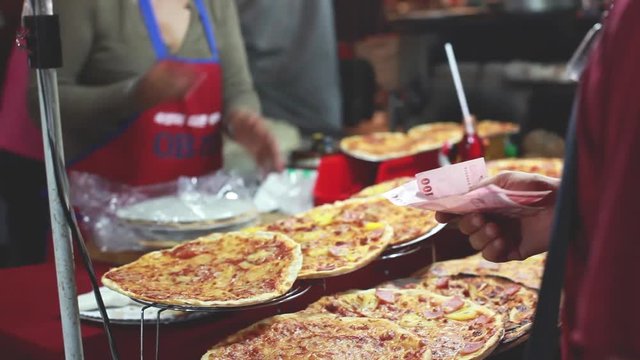 Different types of pizzas on display for sale at the street market in Thailand. Man buys two pizzas. 1920x1080
