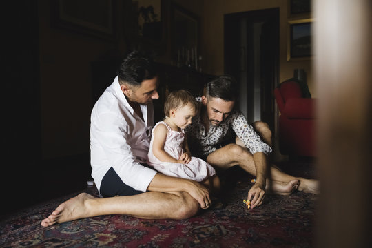 Gay couple playing with their little daughter at home