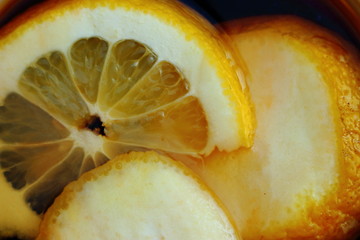 Juicy yellow lemon slices in black tea. Healthy drink and bright food background.