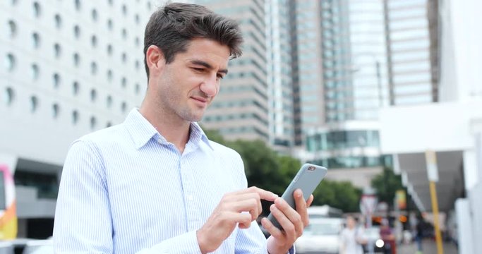 Businessman using cellphone beside the road