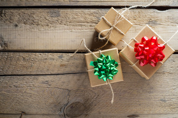 Three craft cardboard gift boxes on a rustic wooden background. Gift kraft boxes with ribbon bow and rope.