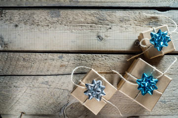 Three craft cardboard gift boxes on a rustic wooden background. Gift kraft boxes with ribbon bow and rope.