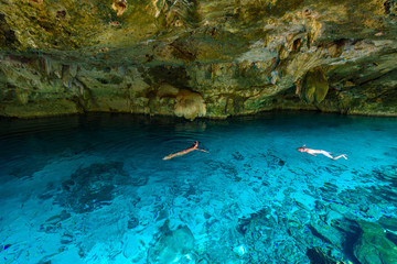 Cenote Dos Ojos in Quintana Roo, Mexico. People swimming and snorkeling in clear blue water. This cenote is located close to Tulum in Yucatan peninsula, Mexico.