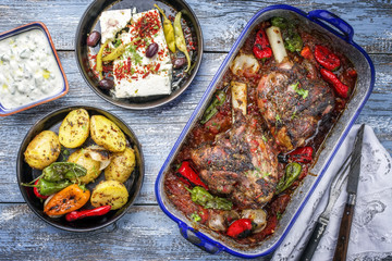 Greek roasted leg of lamb with feta and potatoes in tomato sauce as top view in a skillet © HLPhoto