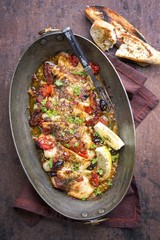 Fried John Dory fish fillet with vegetable and baguette as top-view in a casserole