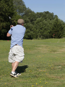 Golfeur frappant une balle avec son club pour la propulser depuis le tee de d&eacute;part sur le parcours.