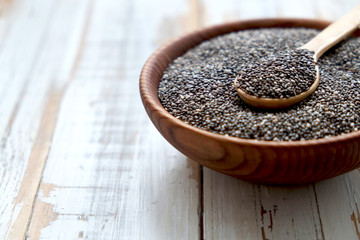 Chia seeds in a wooden spoon on a grained wood, copy space