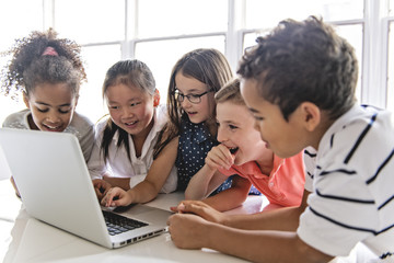Group of curious children watching stuff on the laptop screen