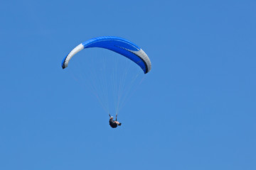 Planeur en vol de parapente sur fond de ciel bleu en été en Savoie.