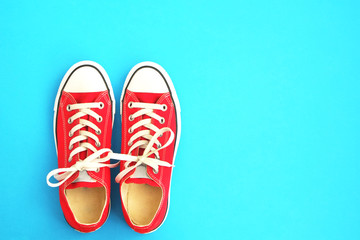 New red sneakers on blue background with copy space. 