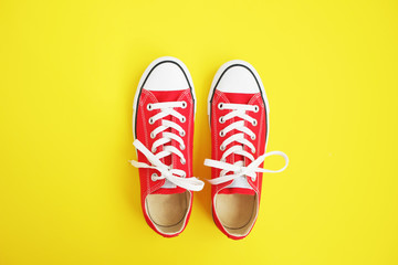 New red sneakers on yellow background with copy space.