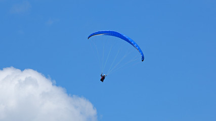  Vol de parapente sur fond de ciel bleu en montagne. Deltaplane au dessus des nuages.