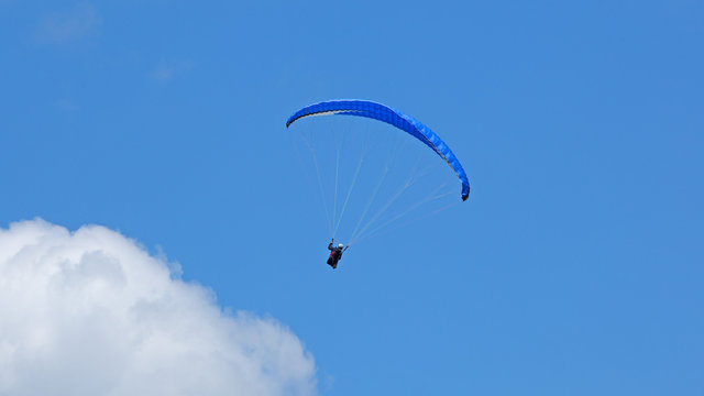  Vol de parapente sur fond de ciel bleu en montagne. Deltaplane au dessus des nuages.